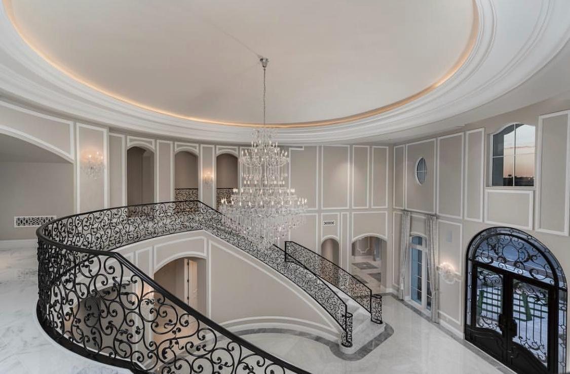 Custom wrought-iron staircase beneath a crystal chandelier